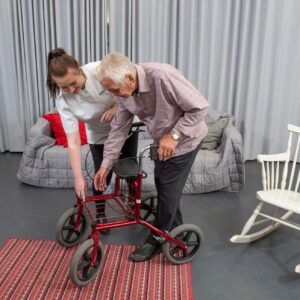 Nainen auttaa vanhusta rollaattorin kanssa.