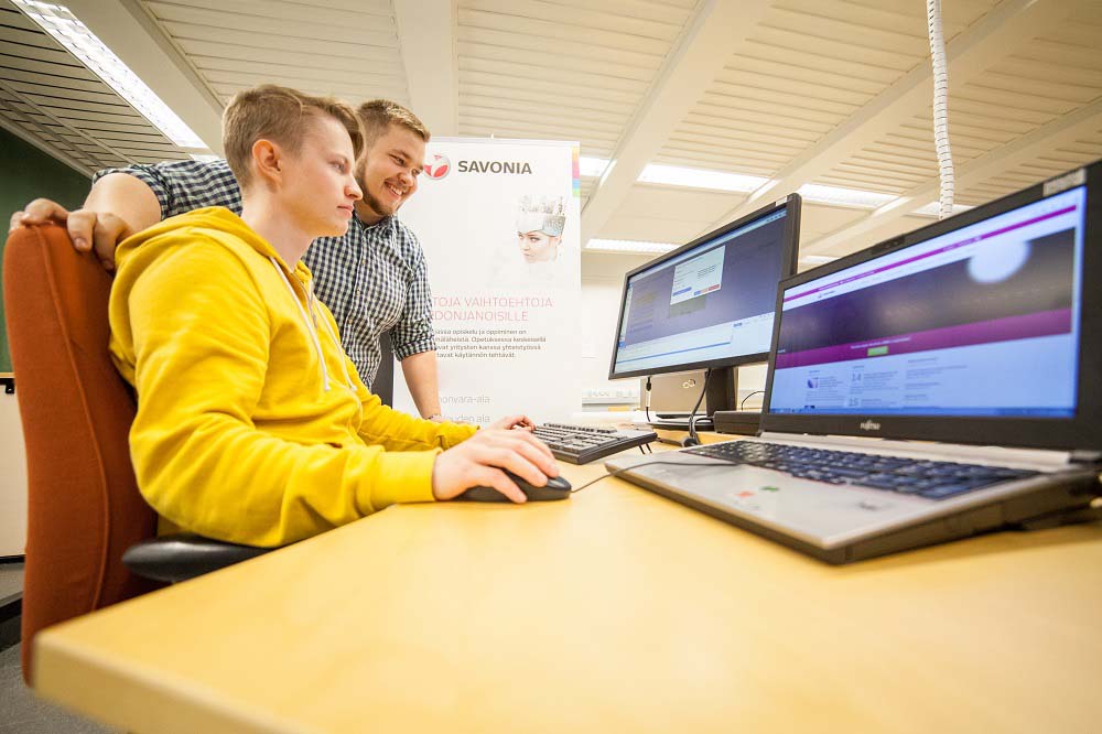 Kaksi opiskelijaa tietokoneen äärellä.