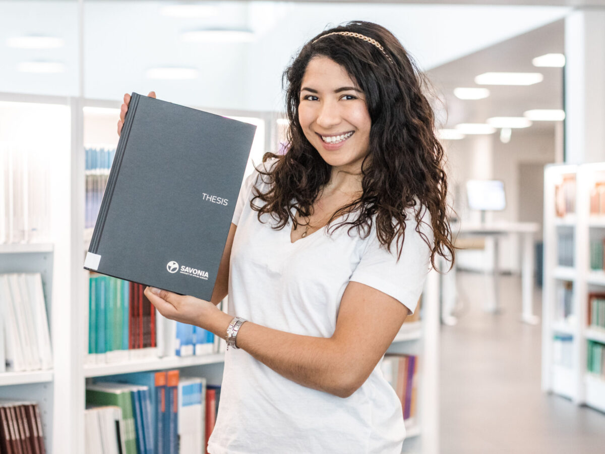 Woman holding a printed thesis on her hands.