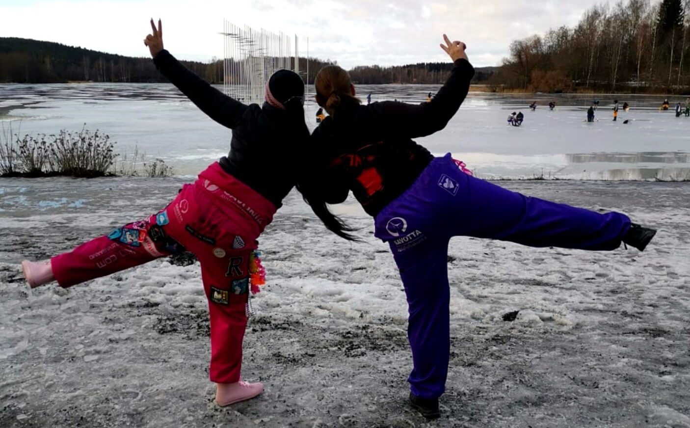 Kaksi tyttöä opiskelijahaalareissa talvisella rannalla.