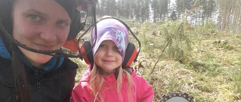 Nainen ja tyttölapsi moottorisahan kanssa metsätöissä.