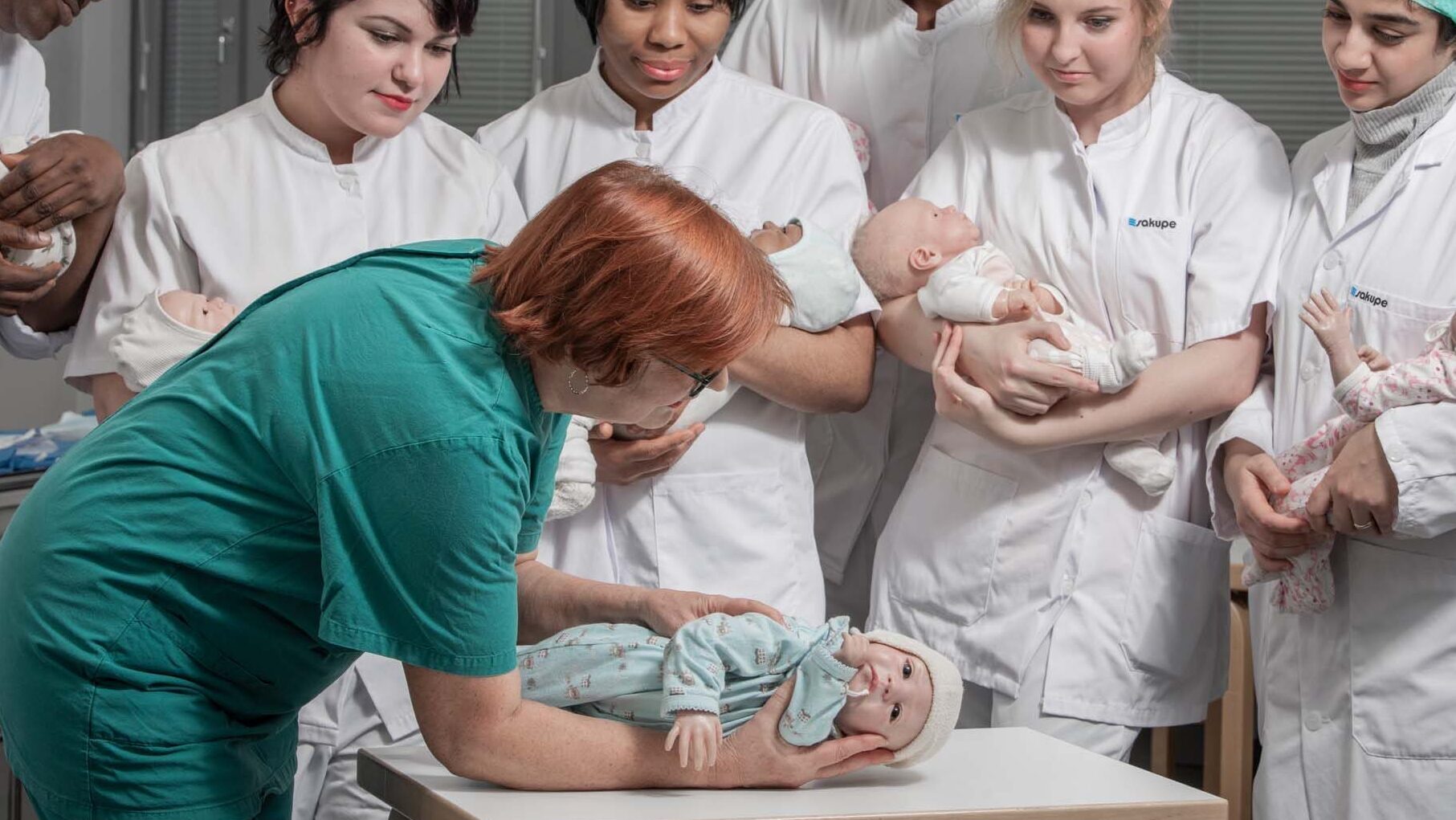 Sairaanhoitajaopiskelijoita ja vauvanukkeja.