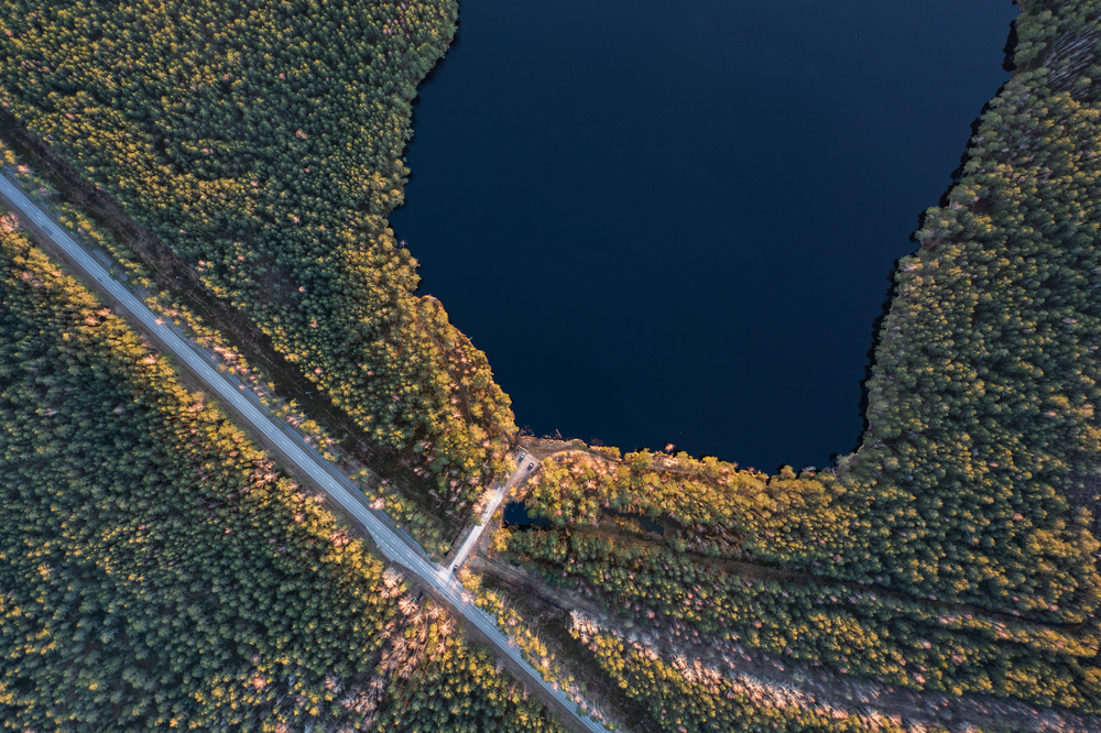 Kuvituskuvassa kuvattu järvimaisema ylhäältä käsin, kuvassa näkyy järven lisäksi metsää ja maantietä.