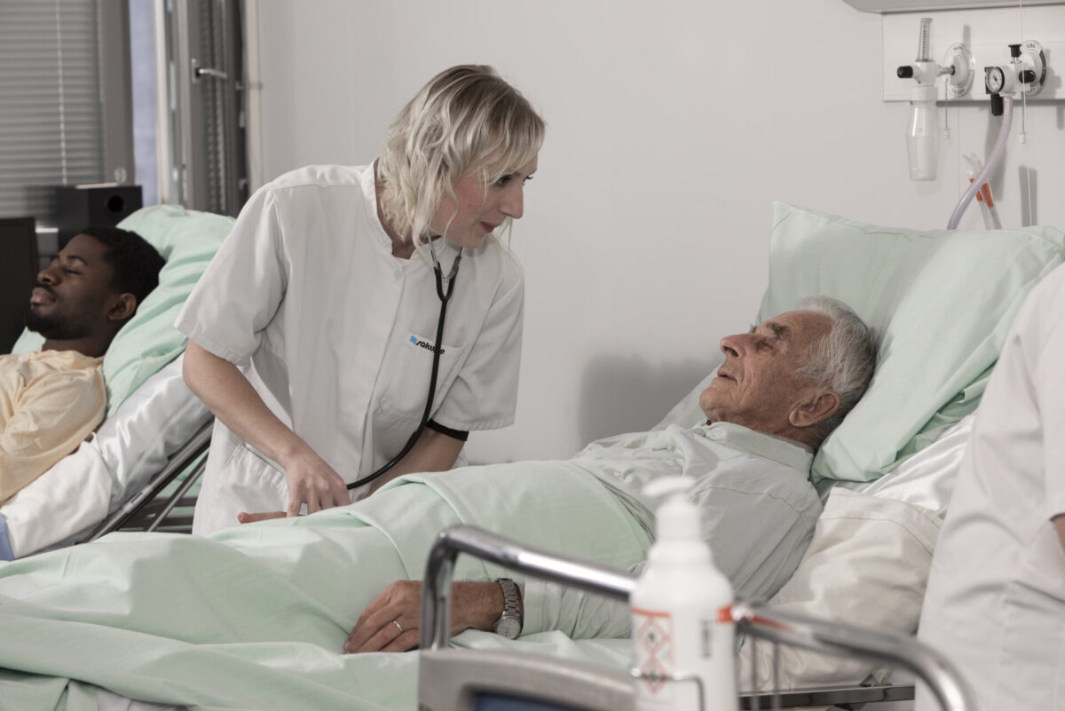 Sairaanhoitaja hoitaa sängyssä makaavaa potilasta