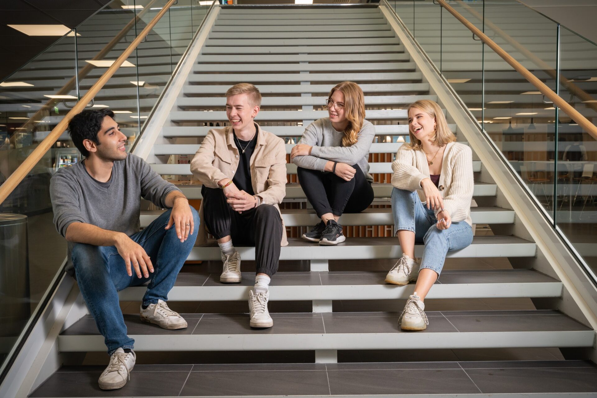 Four students sitting down in the stairs of Savonia's Campus heart.