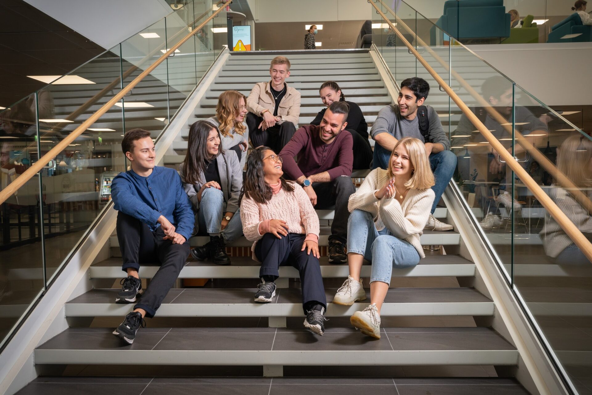 Nine students sitting down in the stairs of Savonia's Campus heart.