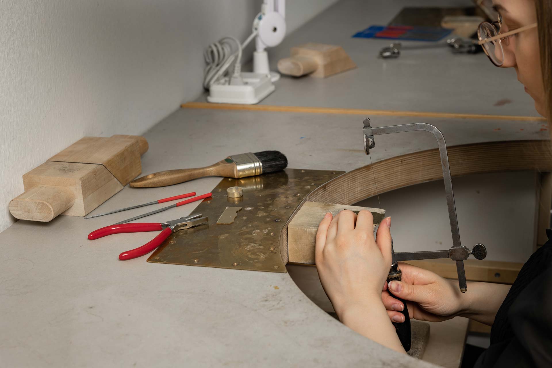 Opiskelija sahaa messinkiä korupajassa.