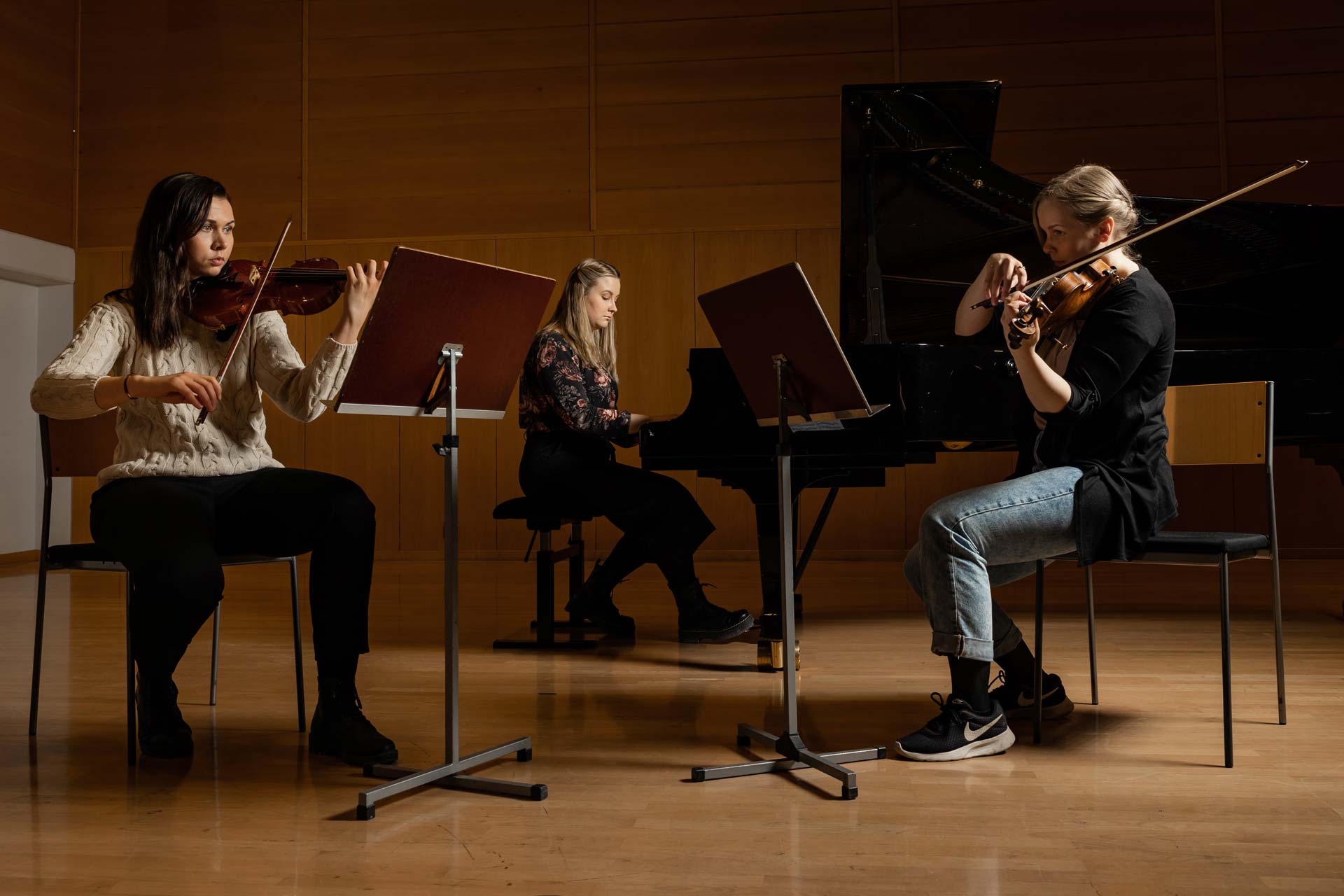 Kaksi viulistia ja pianisti harjoittelevat.