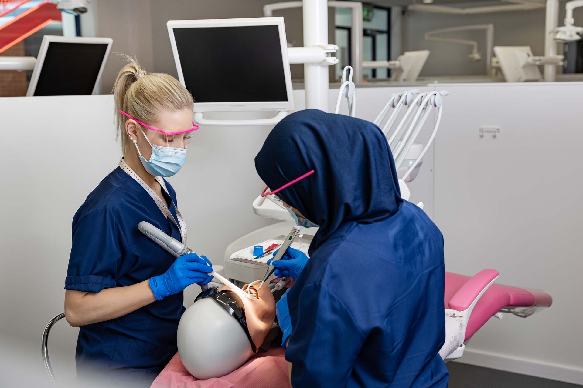 Kaksi suuhygienistiä hoitamassa nukkea.