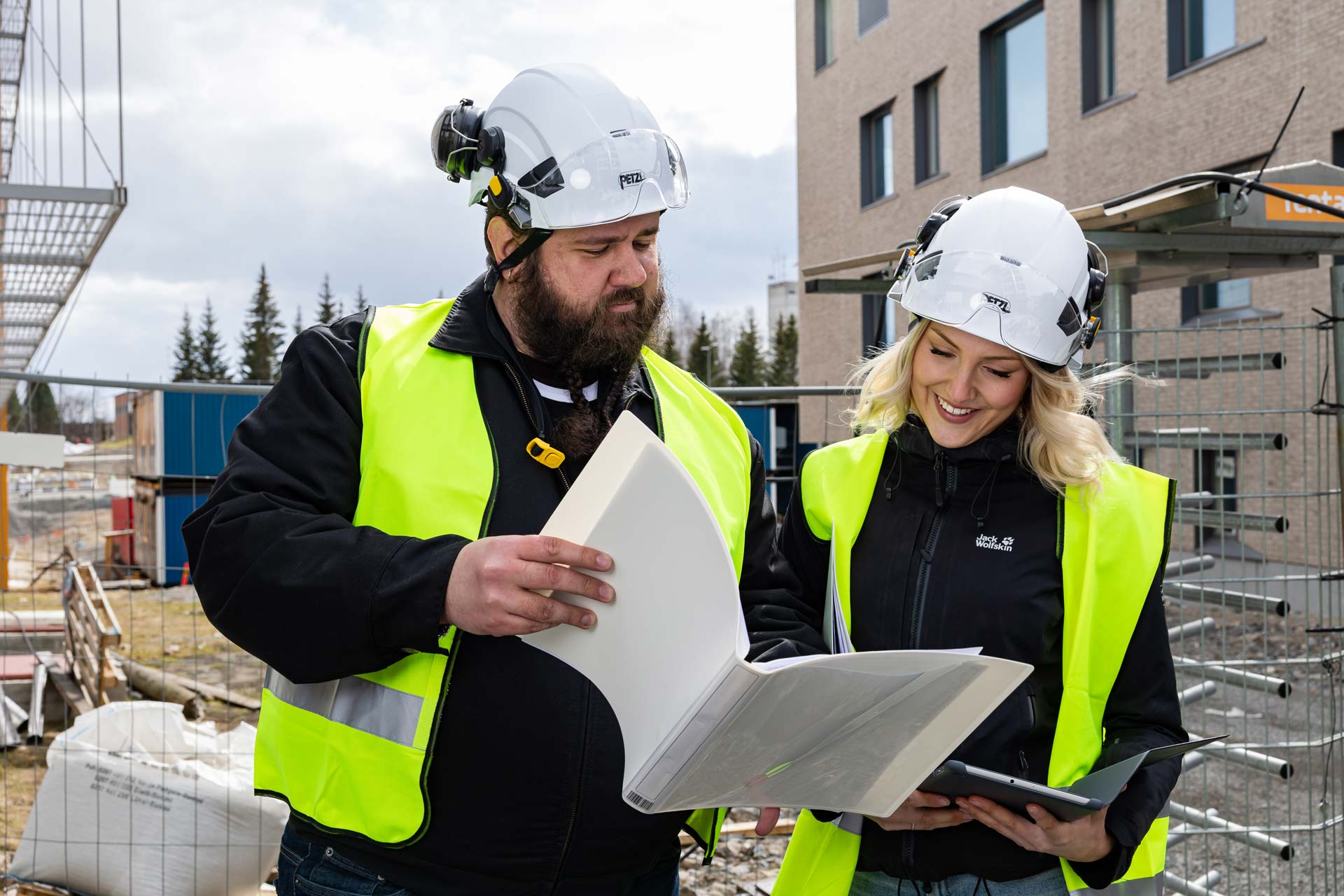 Rakennusmestarit tutkivat piirustuksia rakennustyömaalla.