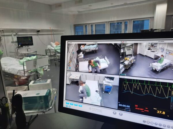 Simulaatiokeskuksen näyttö ja potilassänky.
