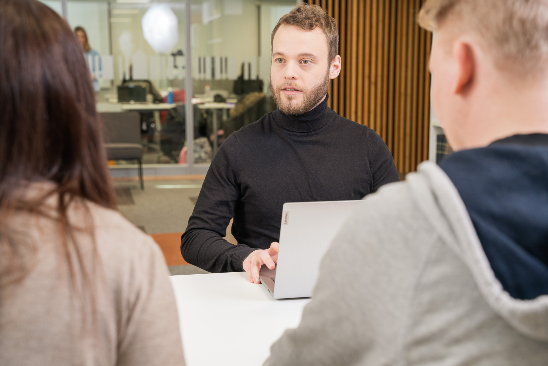 Ryhmä opiskelijoita työskentelee keskustellen saman pöydän ääressä.
