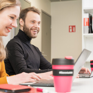 Ryhmä opiskelijoita työskentelee keskustellen saman pöydän ääressä.