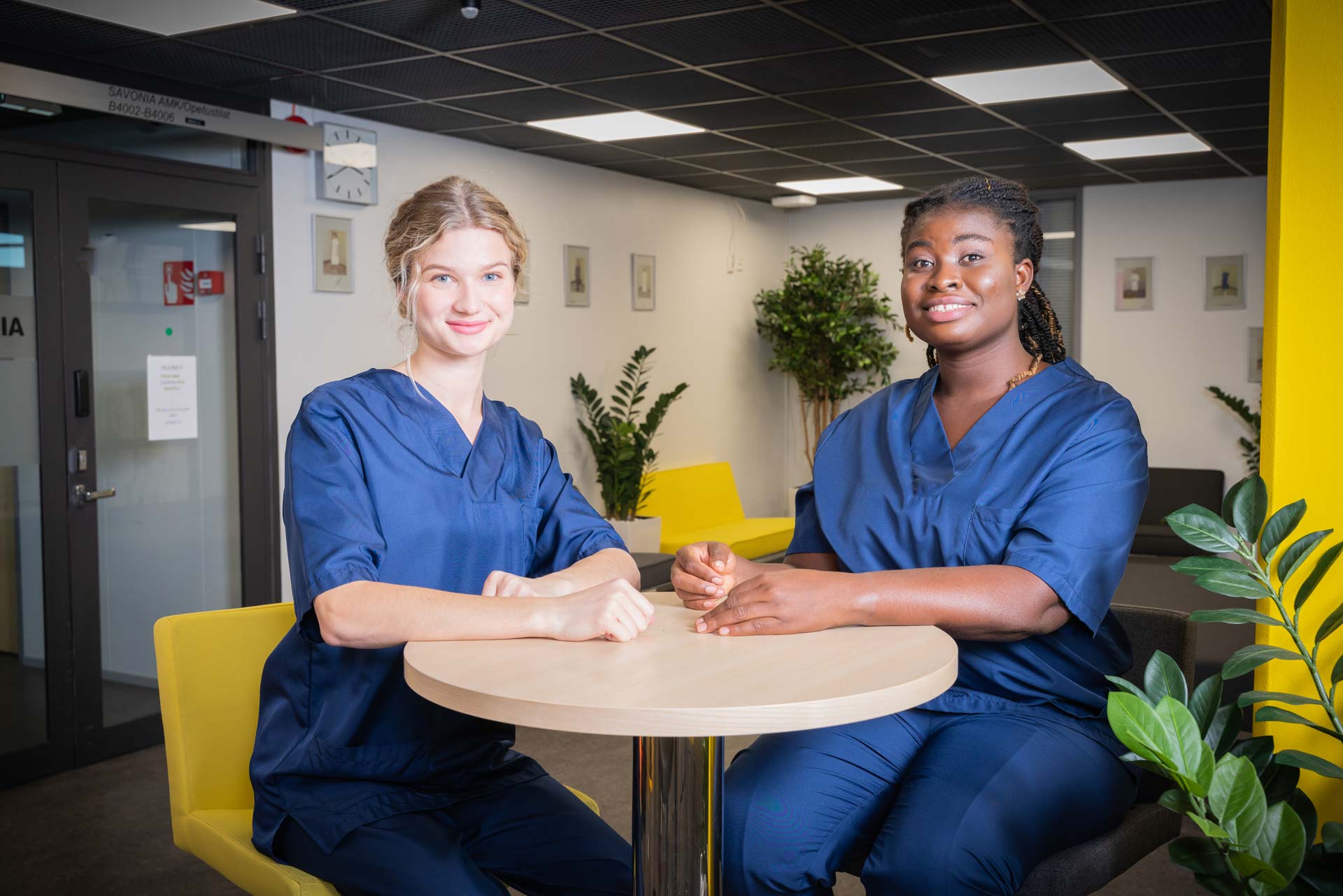 Two nursing students smiling and sitting by a table.