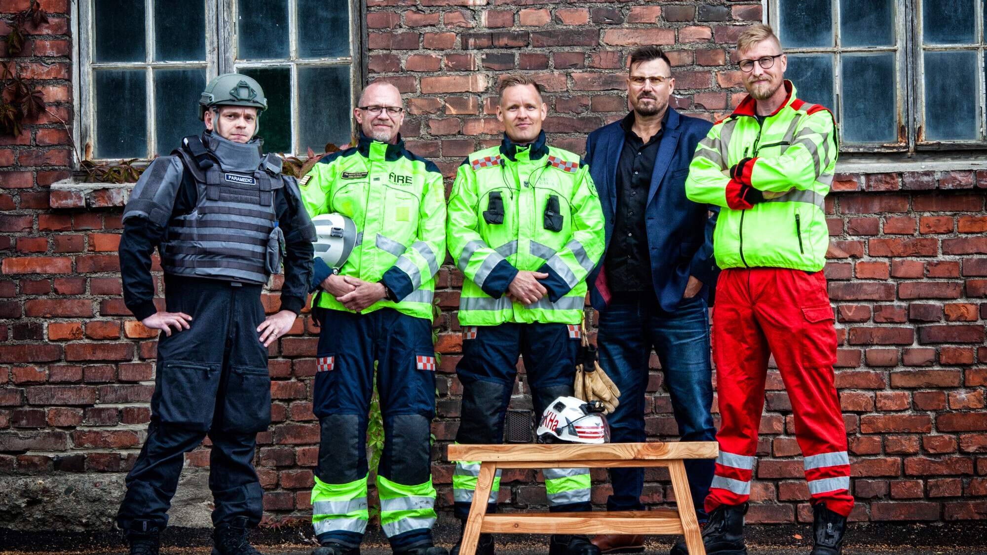 Kouluttajat Marko Kolula, Simo Ekman, Kalle Hakamäki, Harri Gustavsberg ja Marko Tolonen seisomassa tiiliseinän edessä.
