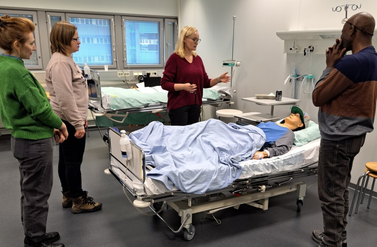 sairaalasängyssä makaavan nukern ympärillä seisoo yksi opettaja ja kolme opiskelijaa.