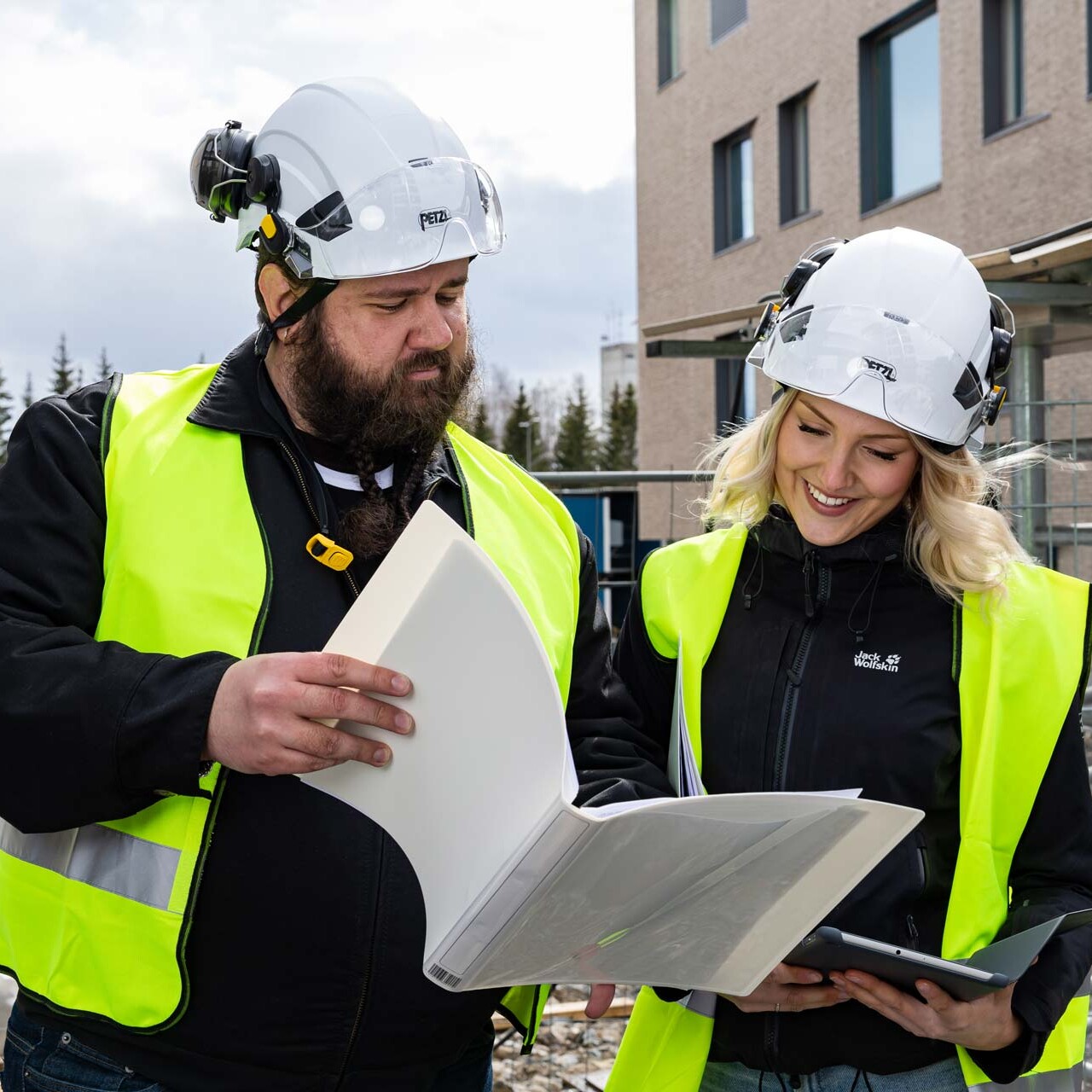 Rakennusmestarit tutkivat piirustuksia rakennustyömaalla.