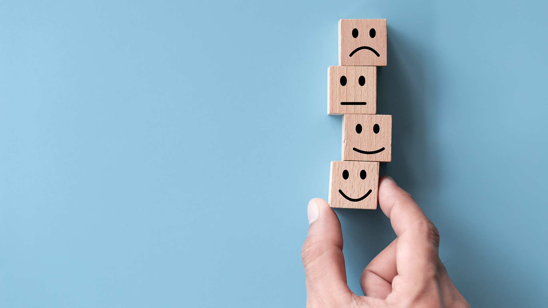 käsi kannattelee puupalikoita, joissa eri ilmeitä