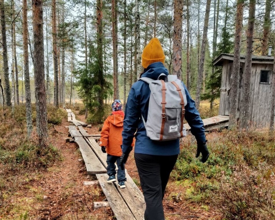 Lapsi ja aikuinen kulkevat metsässä pitkospuilla.