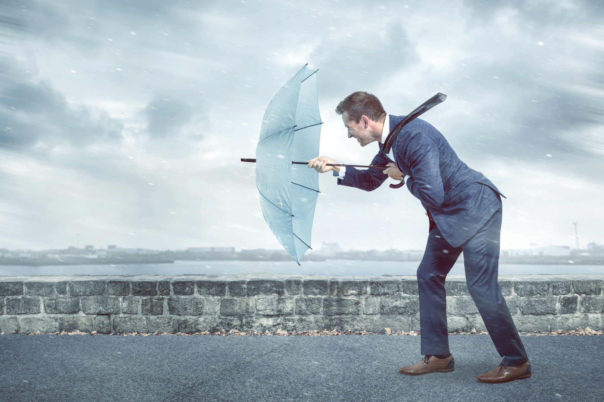 businessman-with-an-umbrella-is-facing-strong-headwind