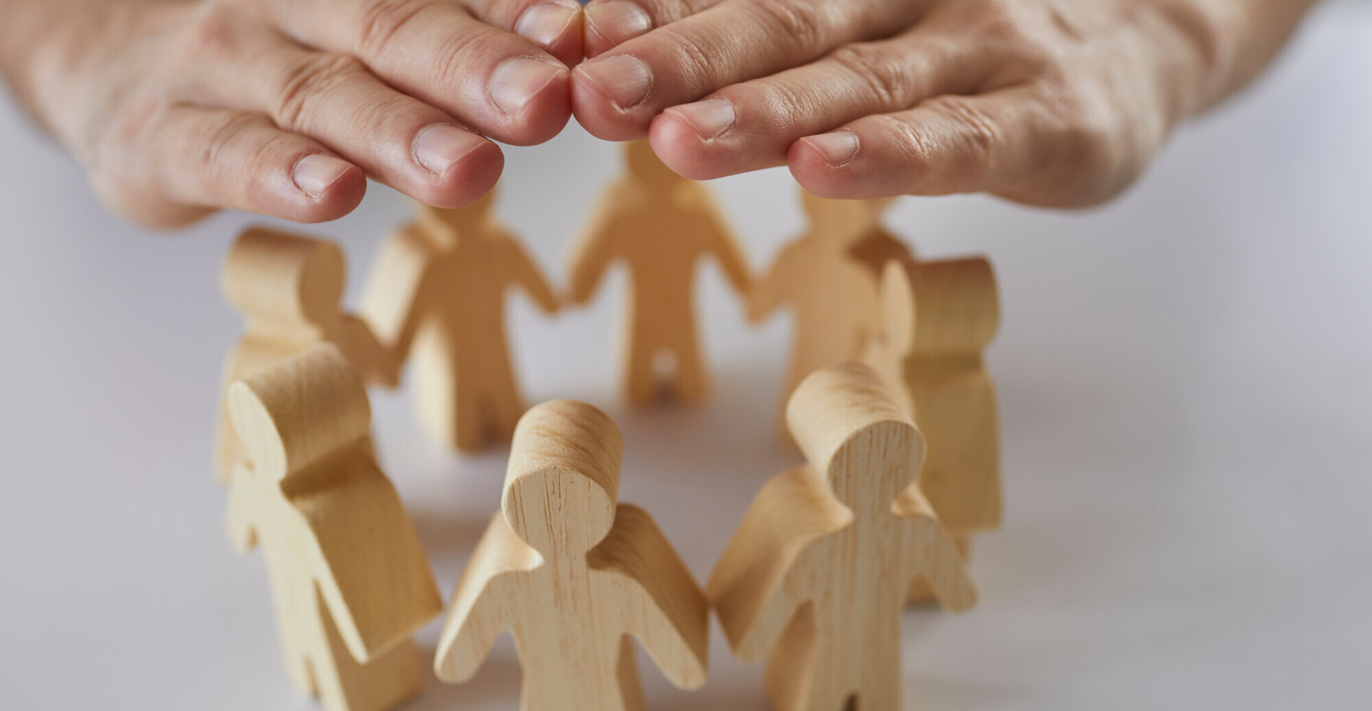 insurance-agents-hands-protect-wooden-figures-of-people-standing-in-circle-in-front-of-him