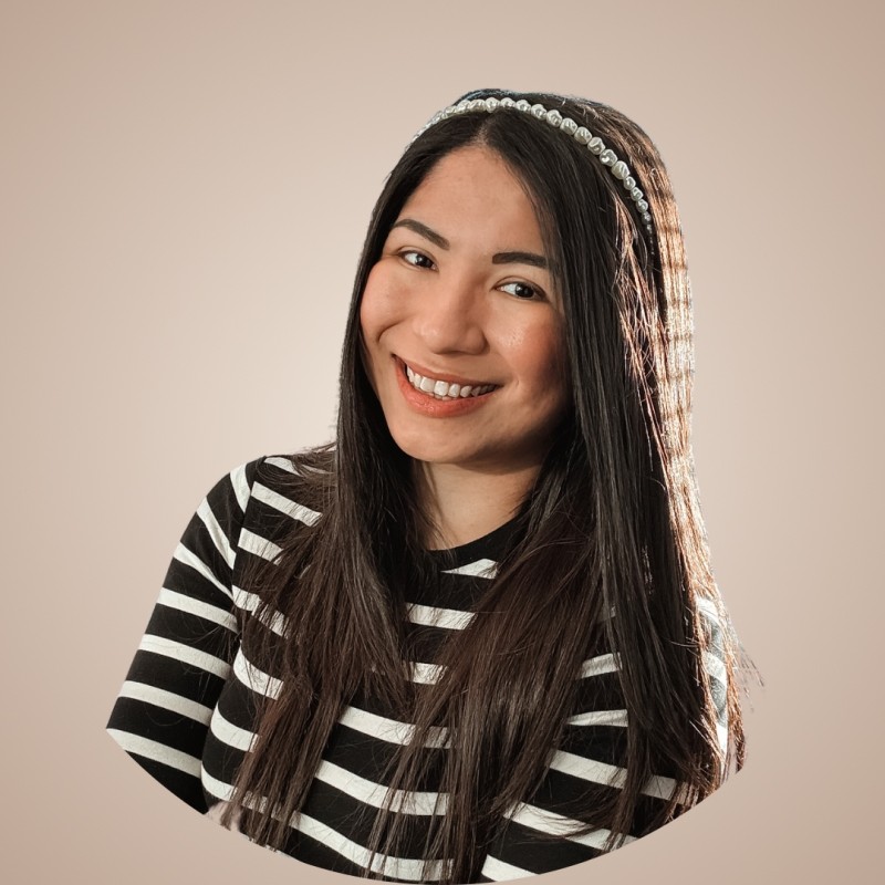 Nainen, jolla on pitkät suorat hiukset, päällään raidallinen mustavalkoinen toppi ja helminauha, hymyilee kameralle beigeä taustaa vasten.