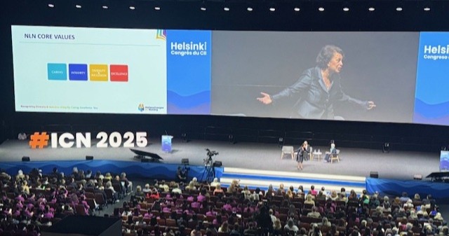 Suuri yleisö osallistuu konferenssiin tilavassa salissa. Puhuja elehtii lavalla lähellä näyttöä, jossa näkyy NLN:n perusarvot ja "Helsinki Congress ICN". "#ICN 2025" on näkyvästi esillä edessä.