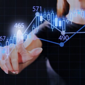 Henkilö koskettaa virtuaalista näyttöä, jossa näkyy hehkuva rahoituskaavio, jossa on numeroita ja kynttilänjalka-arvoja, jotka symboloivat pörssitietojen analysointia ja digitaalista kaupankäyntiä.
