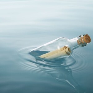 Lasipullo, jossa on korkki, kelluu tyynellä vedellä, ja sen sisällä on kääritty paperi tai viesti. Pulloa ympäröi kevyesti aaltoilu.