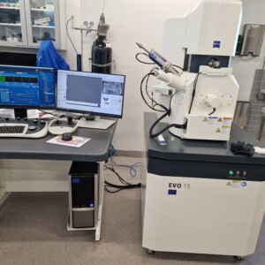 Laboratorio, jossa on EVO 15 -niminen pyyhkäisyelektronimikroskooppi, jonka vieressä on työpiste, jossa on kaksi näyttöä, joilla näytetään tieteellisiä tietoja, näppäimistö, tietokonehiiri ja ohjauspaneelit.