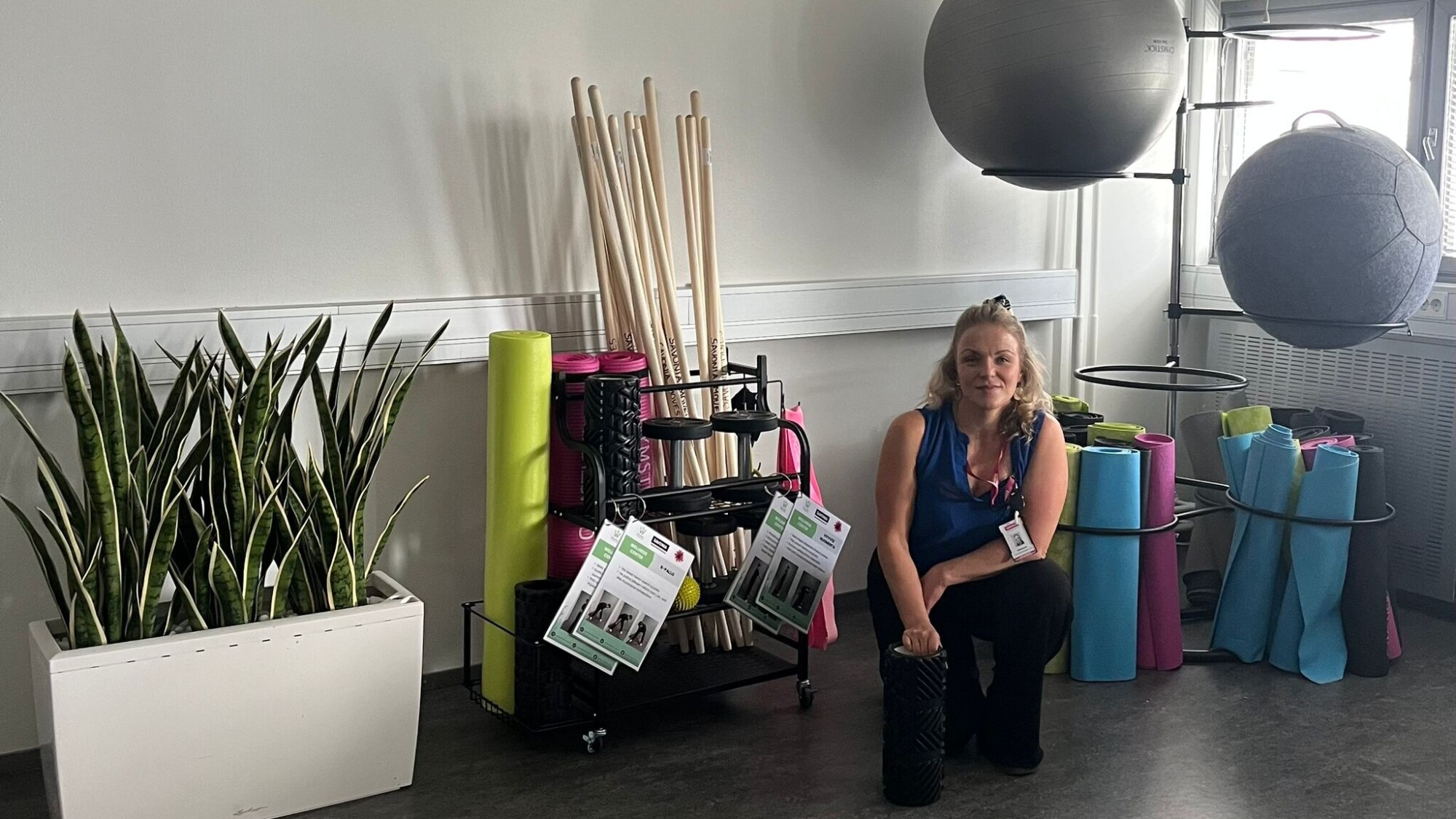 Nainen istuu kuntosalin lattialla.