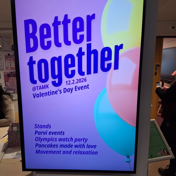 Digitaalisessa kyltissä lukee: Paremmin yhdessä @TAMK 12.2.2026 Ystävänpäivätapahtuma. Alla on lueteltu aktiviteetteja: Ständejä, Parvi-tapahtumia, Olympialaisten katselubileet, Rakkaudella tehtyjä pannukakkuja, Liikuntaa ja rentoutumista. Taustalla on värikkäitä ilmapalloja.