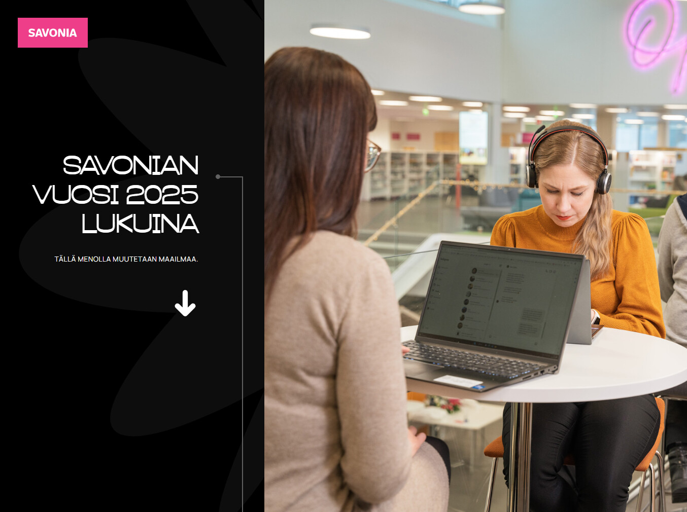 Kaksi naista istuu pöydän ääressä modernissa sisätilassa. Toinen nainen on kameraan päin kuulokkeet päässä ja työskentelee kannettavalla tietokoneella, kun taas toinen nainen istuu häntä vastapäätä. Vasemmalla teksti: Savon vuosi 2025 lukuina.