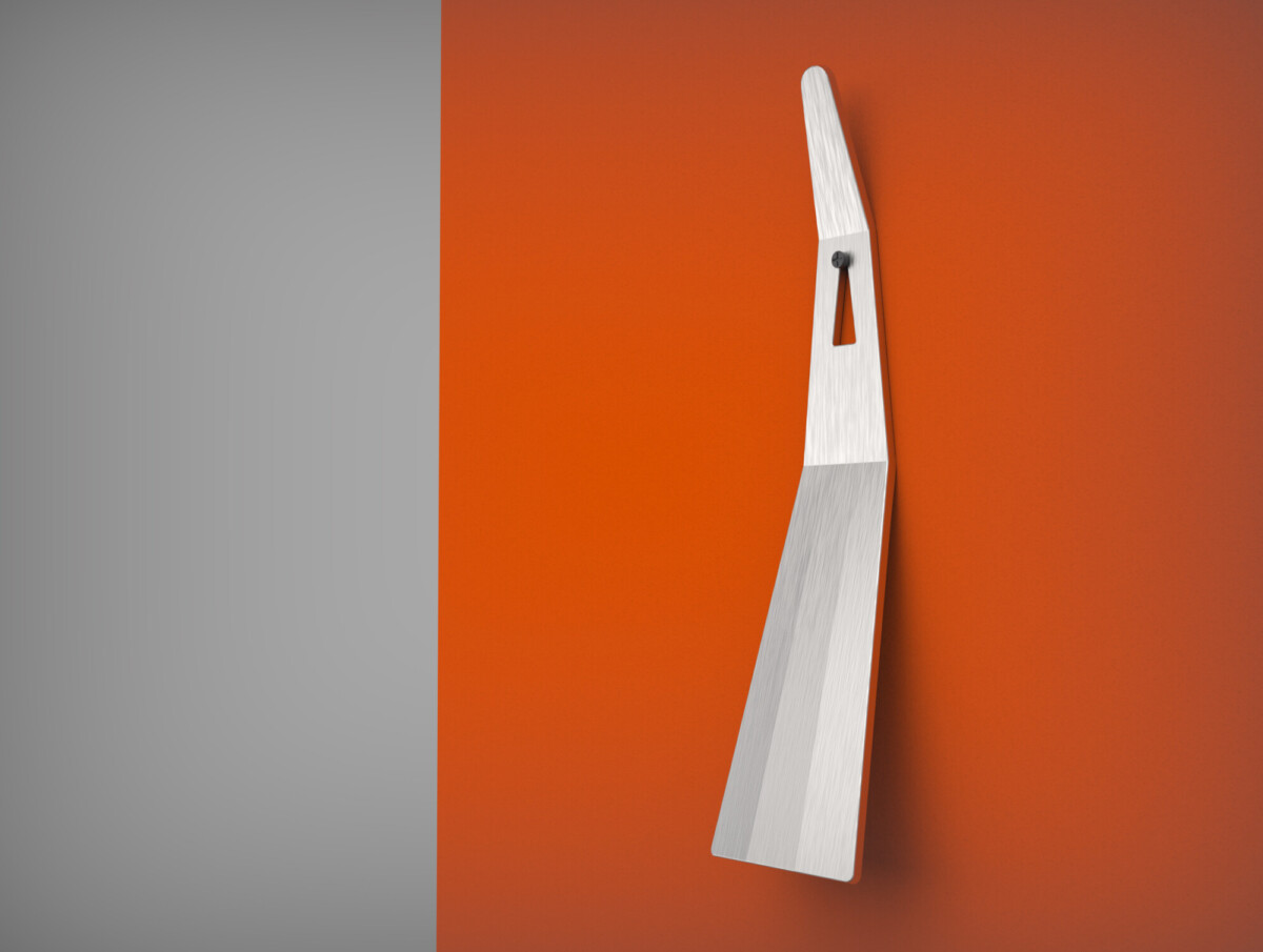 Moderni, hopeinen lastauslasta, jossa on kulmikas kahva, on asennettu pystyasentoon oranssiin seinään, harmaan pystysuoran kaistaleen viereen, mikä luo minimalistisen ja kontrastisen sommitelman.