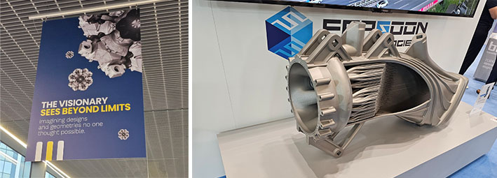 Vasemmanpuoleisesta katosta roikkuu kyltti, jossa lukee The visionary sees beyond limits, kun taas oikeanpuoleisessa kuvassa monimutkainen metallinen teollinen komponentti on esillä näyttelyn osastolla.