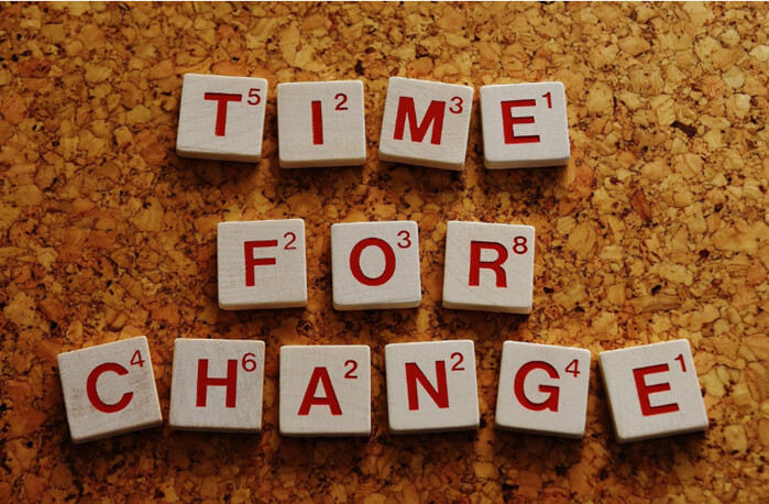 Scrabble-laatat korkkitaululla, joissa lukee TIME FOR CHANGE, ja jokaisen kirjaimen kulmassa näkyy laattaa vastaava pistemäärä.