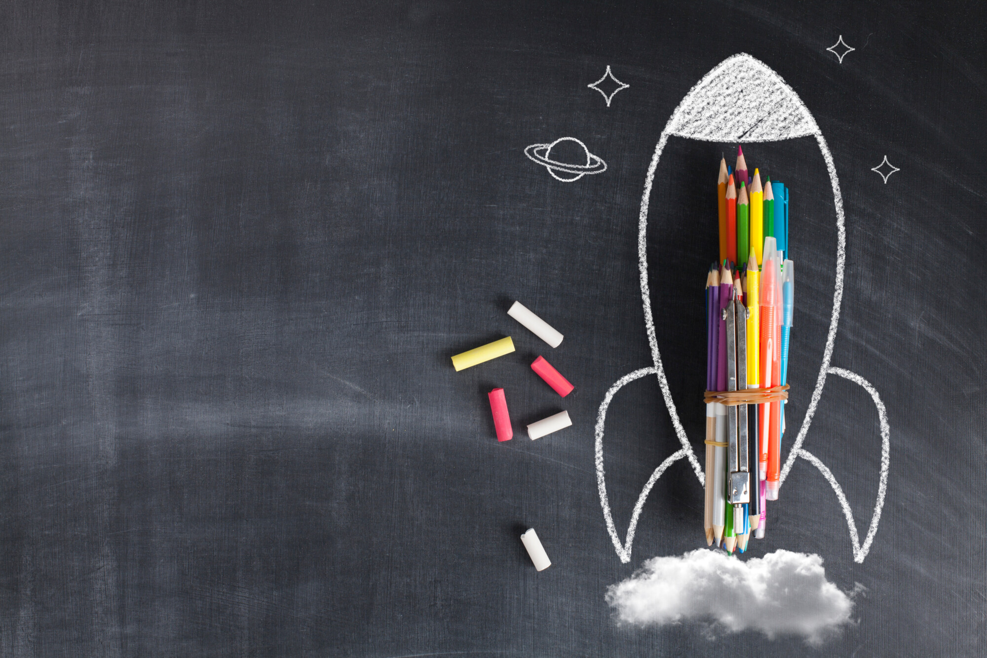 Värikynät on aseteltu kuin raketti liitutaululle, ja niissä on liitulla piirretty raketin ääriviivat, tähdet ja planeetta. Värilliset liitupalat ja liitupilvet parantavat mielikuvituksellista maisemaa.