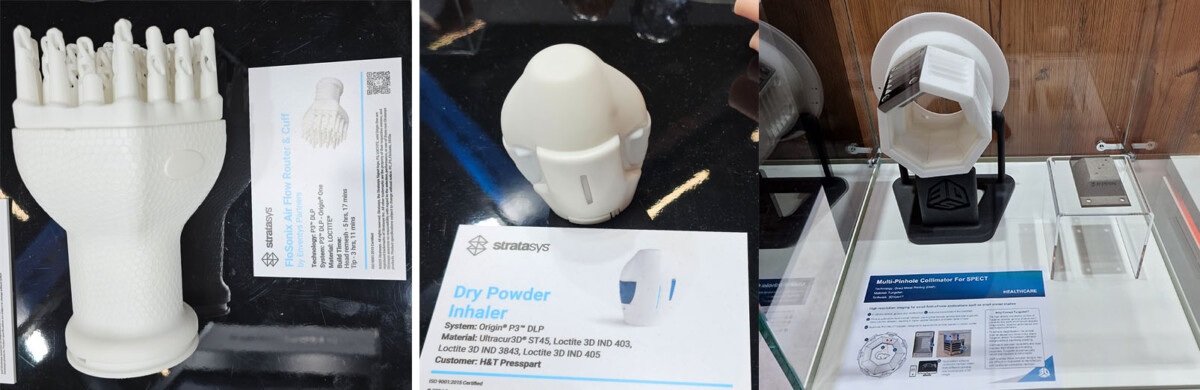 Kolme valokuvaa 3D-tulostetuista lääkinnällisistä laitteista, jotka ovat esillä selkeillä jalustoilla, mukaan lukien kuiva-aineinhalaattorin malli, ja jokaisessa on tiedotuskortti, jossa kuvataan laitteen ominaisuuksia ja valmistustietoja.
