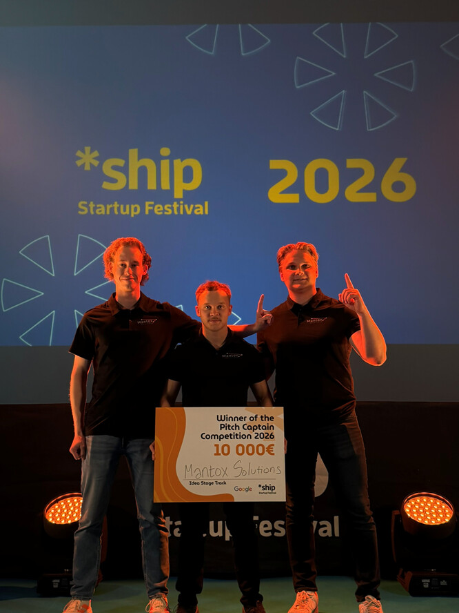 Lavalla seisoo kolme mustiin paitoihin pukeutunutta henkilöä, joilla on kädessään suuri 10 000 euron shekki, jossa lukee Mantox Solutionsin Pitch Captain Competition 2026 -kilpailun voittaja. Heidän takanaan on *ship Startup Festival 2026 -kyltti.