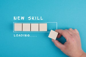 Käsi asettaa puupalikan palikkariviin osittain täytetyssä etenemispalkissa. Yläpuolella lukee NEW SKILL ja alapuolella LOADING..... sinisellä pohjalla, mikä symboloi taitojen kehittymistä.