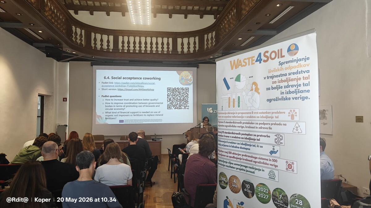 Esityksen dia otsikolla 6.4. Yhteiskunnallinen hyväksyntä coworking näytetään projektorinäytöllä. Oikealla puolella on banneri, jossa lukee WASTE4SOIL ja lisätietoja jätteiden vähentämisestä. Yleisö istuu valkokangasta vasten.