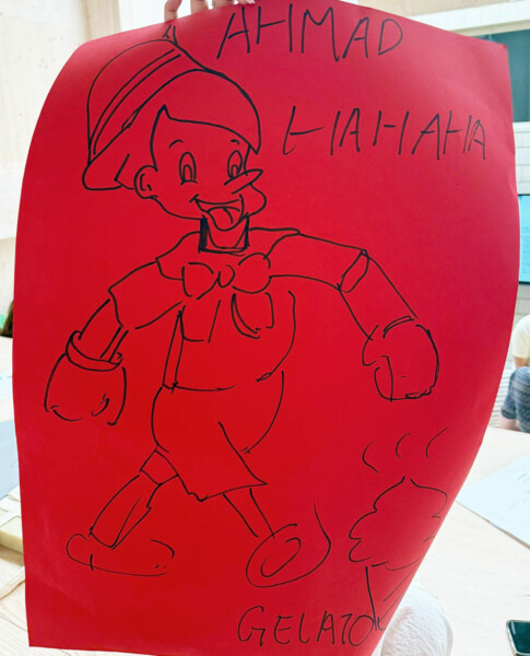 Käsin piirretty luonnos Pinokkiosta punaiselle paperille, jonka ympärille on kirjoitettu sanat AHMAD, LIAHAHA ja GELATO.