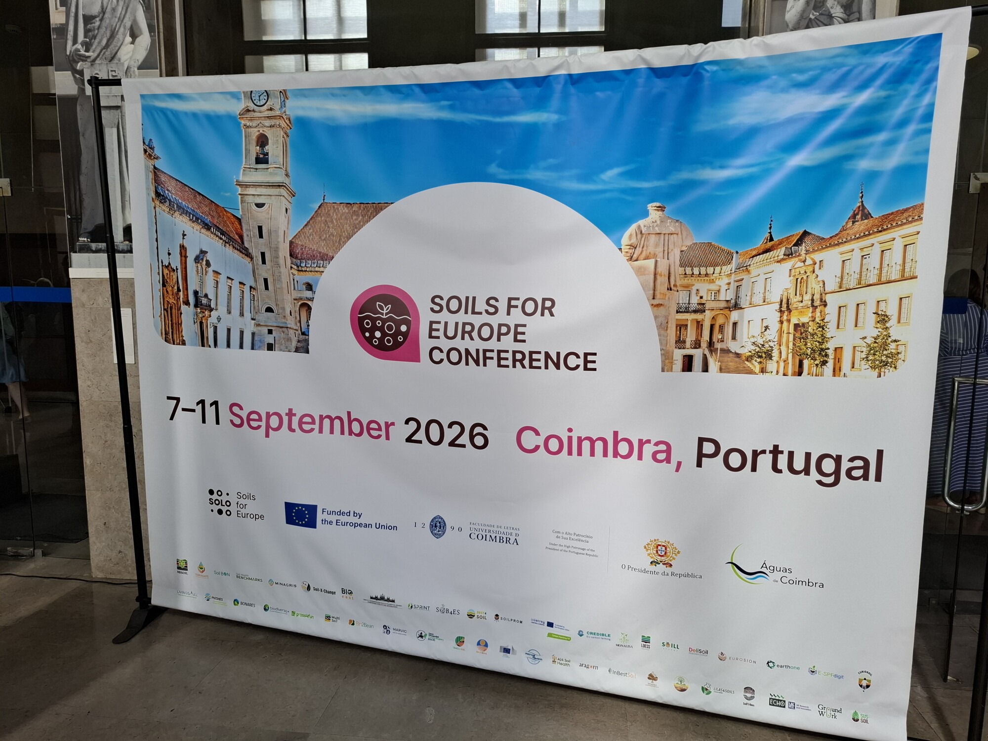 ”Soils for Europe” -konferenssin banneri, joka järjestetään 7.–11. syyskuuta 2026 Coimbrassa, Portugalissa; bannerissa on Euroopan unionin logot ja taustalla Coimbran historiallisia rakennuksia.