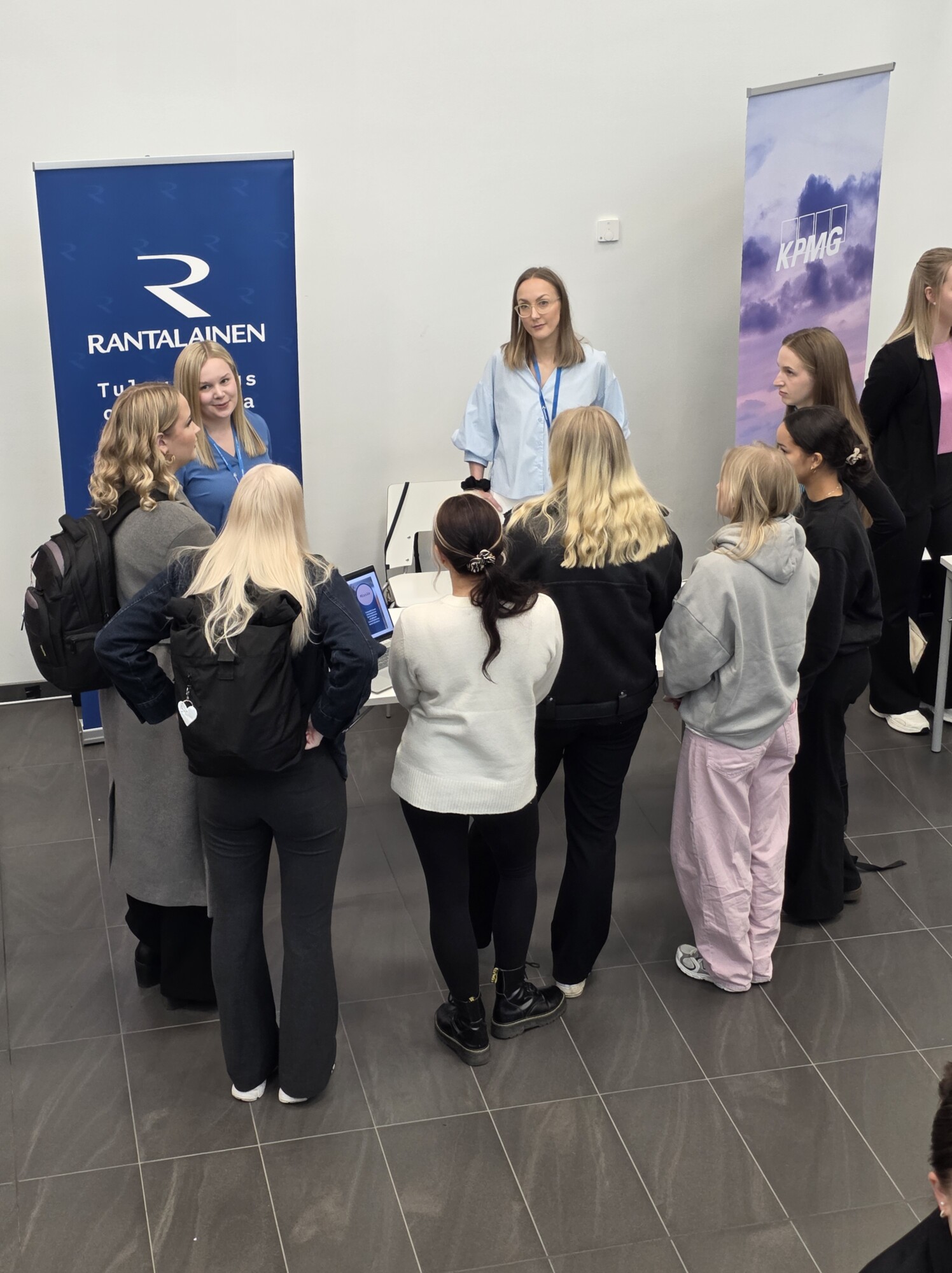 Pöydän takana seisova nainen puhuu opiskelijaryhmälle Rantalaisen uramessujen osastolla.