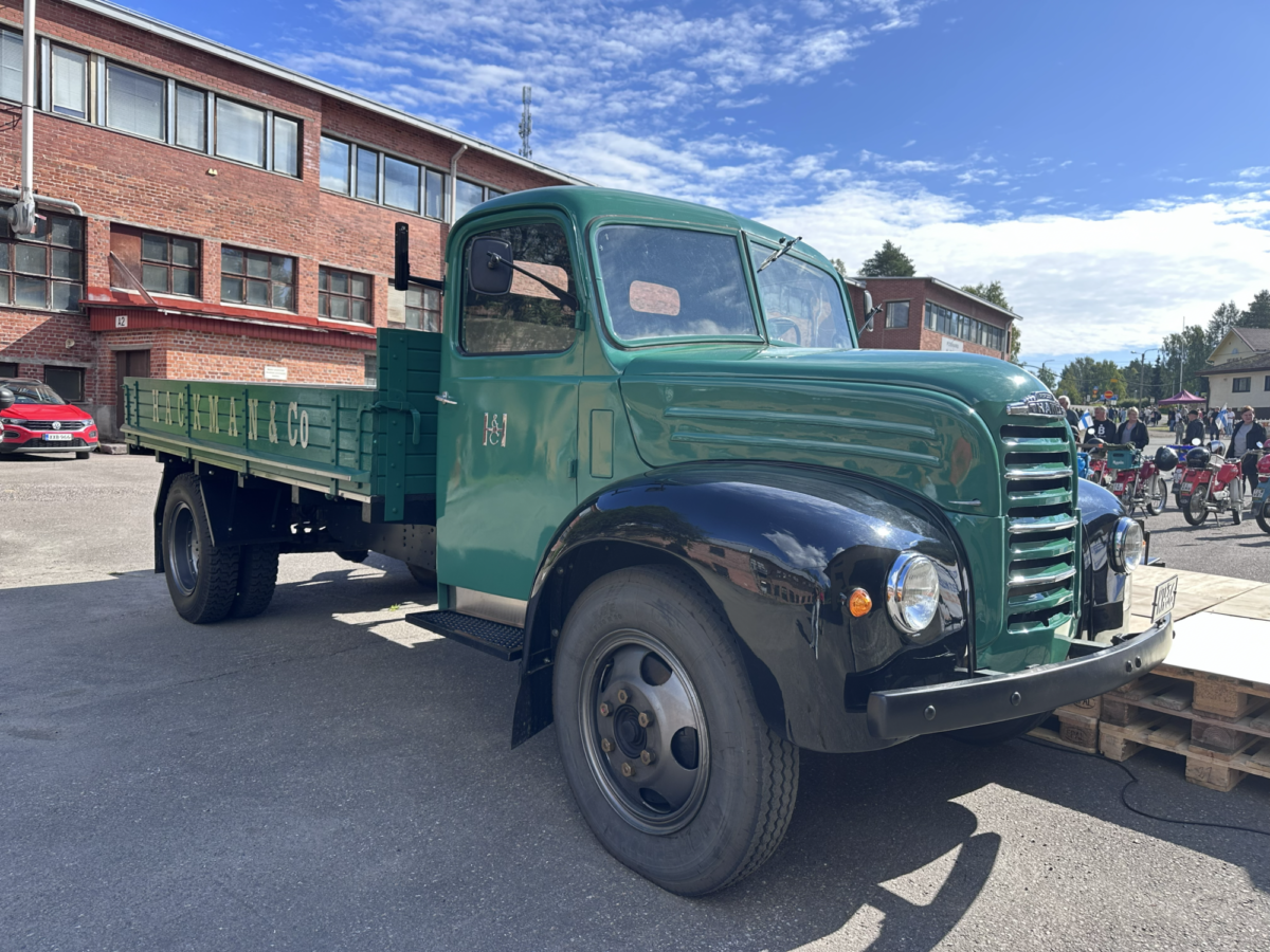 Vintage-tyylinen vihreä ja musta lava-auto oli pysäköity ulkoilma-parkkipaikalle tiilirakennuksen lähelle.