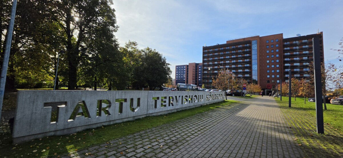 Aurinkoisena päivänä monikerroksisen rakennuksen edessä on betonikyltti, jossa lukee TARTU TERVISHOIU KÕRGKOOL.